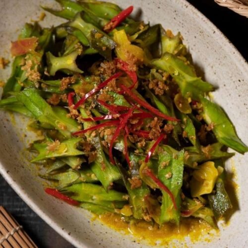 Winged bean stir fry with garlic, chili, and spices served on a rustic dish